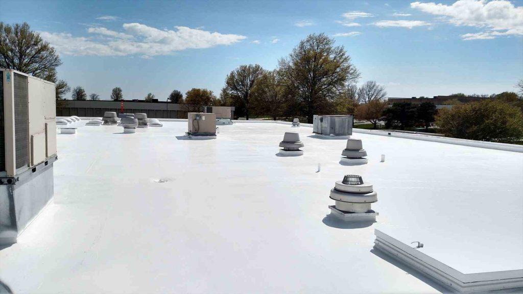 Finished silicone-coated commercial flat roof with rooftop equipment and clear blue sky