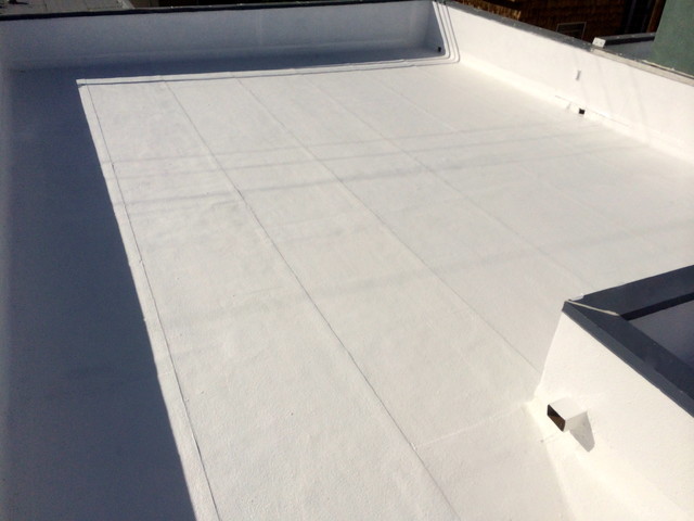 Fresh silicone coating on a small commercial flat roof with reinforced parapet