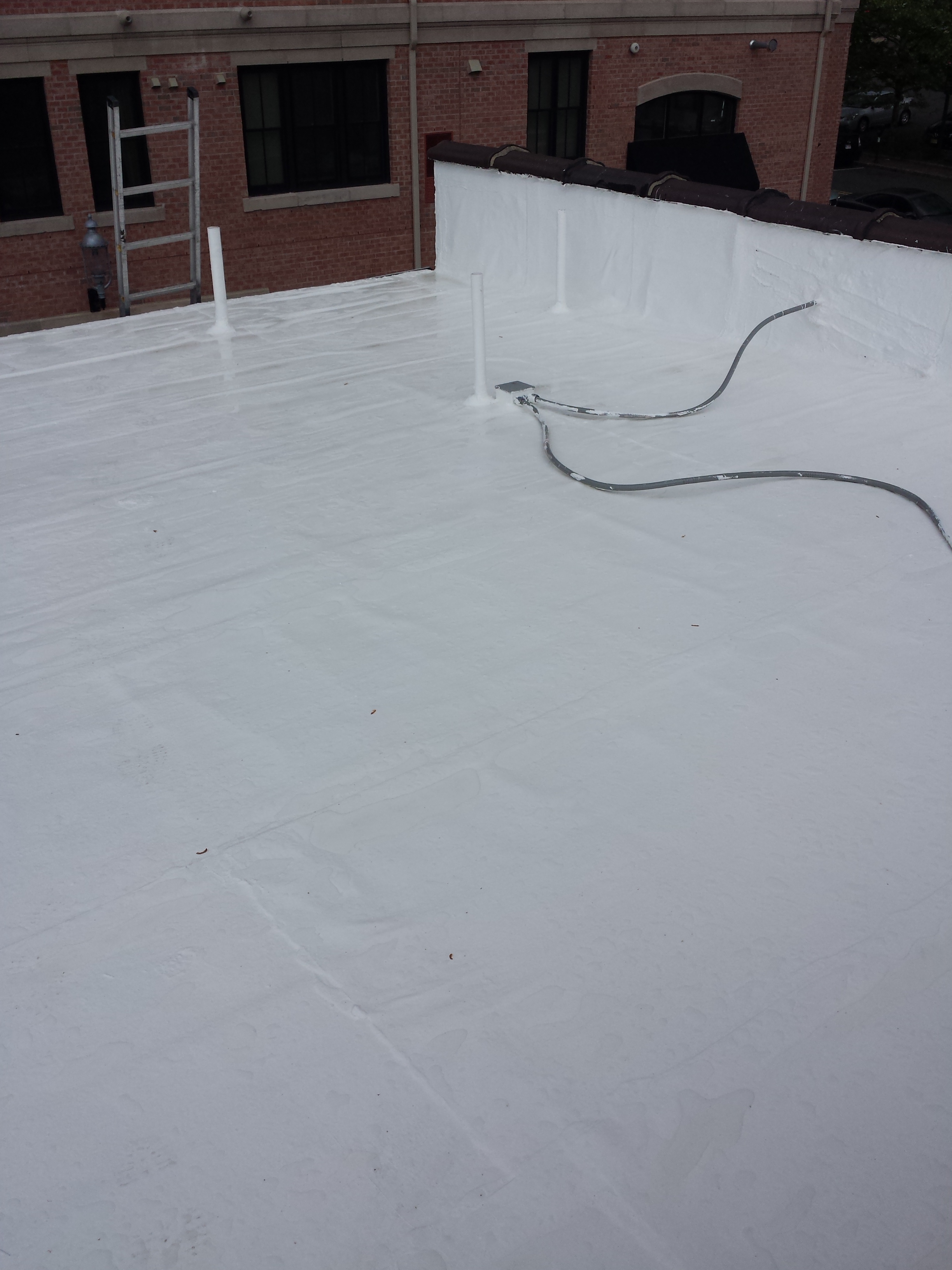Close-up of a silicone-coated roof parapet and deck with reinforced edge detail