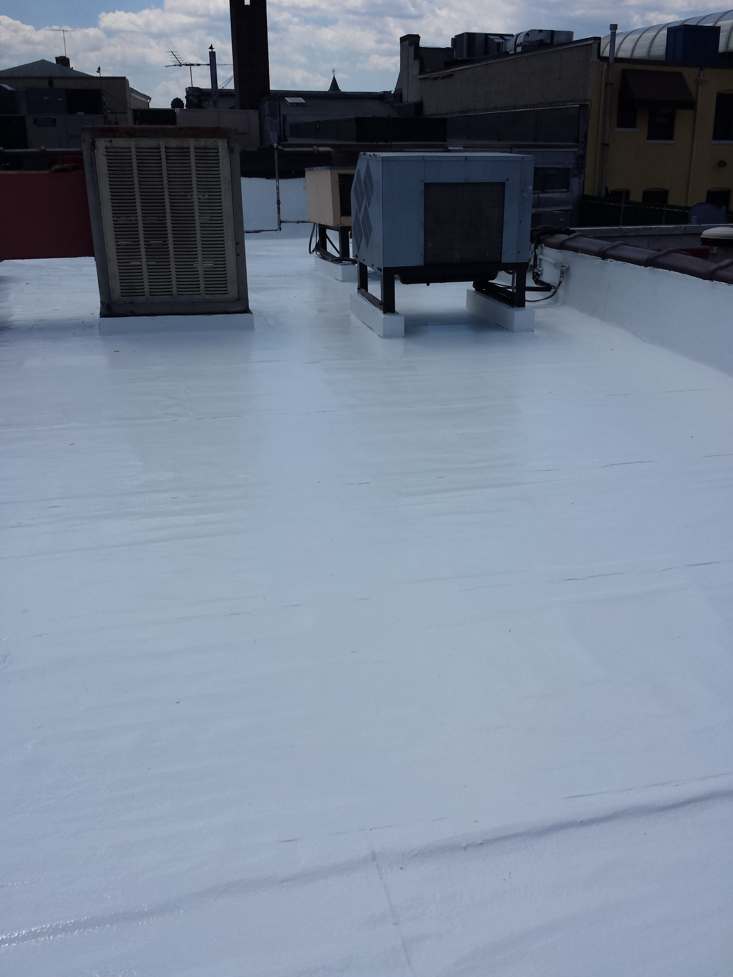 Urban rooftop restored with silicone coating surrounding HVAC equipment