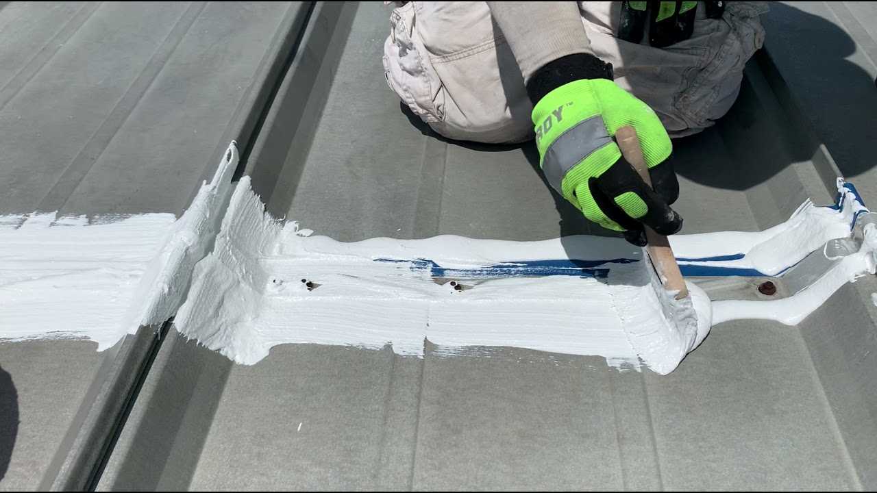 Cleveland Roof Coatings crew applying silicone coating by hand at a metal roof seam