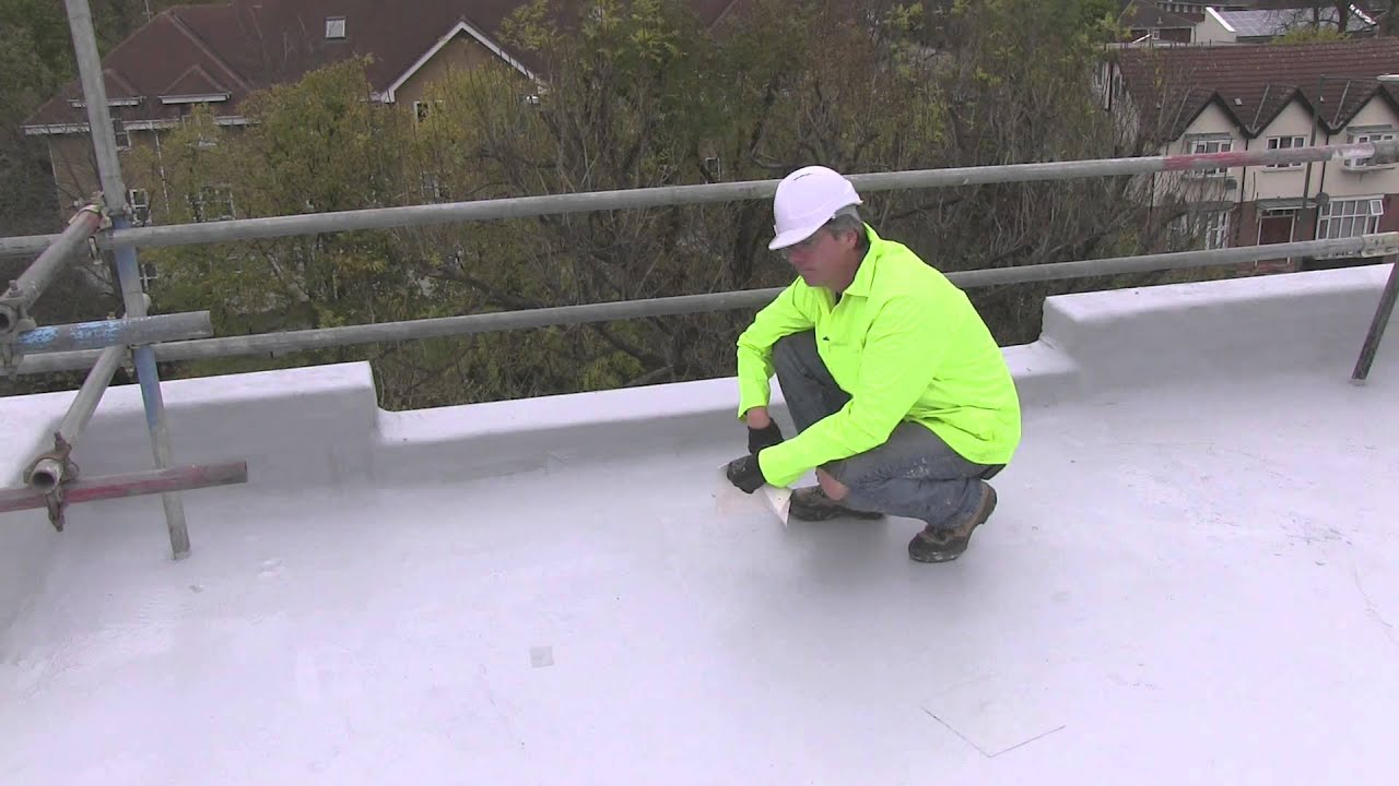 Crew member in high-visibility gear working on a freshly coated rooftop
